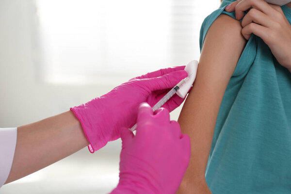 Doctor vaccinating little girl in hospital, closeup. Health care