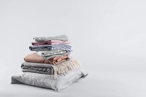 Stack of clean bed sheets and pillow on white background. Space for text