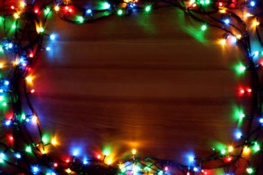 Blurred view of frame made with colorful Christmas lights on wooden background