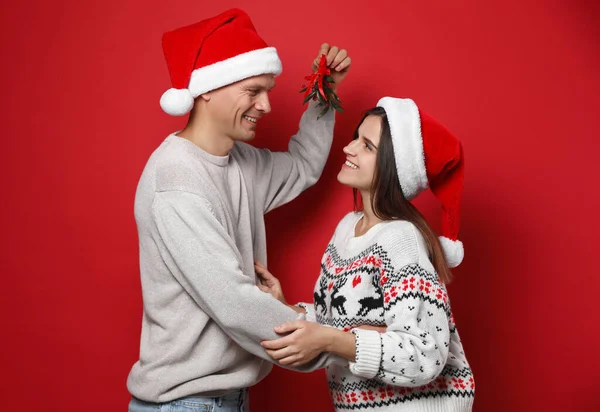 Feliz Pareja Santa Sombreros Pie Bajo Muérdago Manojo Rojo Fondo —  Fotos de Stock