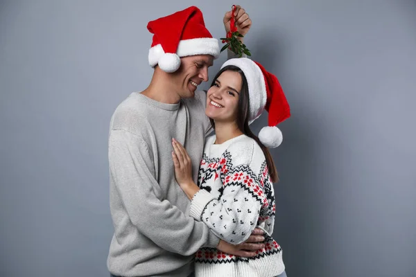 Casal Feliz Chapéus Papai Noel Sob Bando Visco Fundo Cinza — Fotografia de Stock