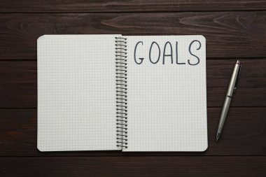 Kalem ve gol listeli defter tahta masada, düz yatıyordu.