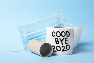Tuvalet kağıdı metni ile rulo Elveda 2020 ve açık mavi arka planda tıbbi yüz maskesi