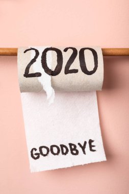 Tuvalet kağıdı, pembe arka planda 2020 'ye güle güle mesajı ile yuvarlanıyor.