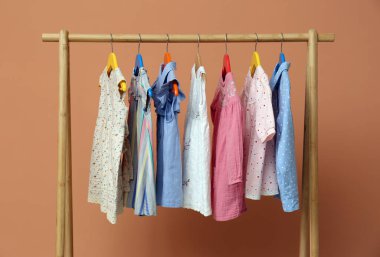 Bej arka planda şık çocuk kıyafetleri.