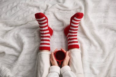 Ekose örgü üzerinde, sıcak kış içeceğiyle rahatlayan bir kadın. Sıcak mevsim