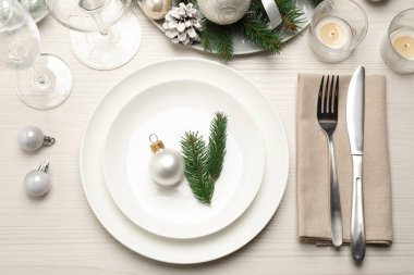 Güzel bulaşık takımları ve beyaz ahşap arka planda Noel dekoru olan şenlik masası.