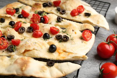 Gri masada zeytinli ve domatesli lezzetli Focaccia ekmeği, yakın plan.