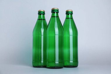 Beyaz zemin üzerinde su olan cam şişeler.