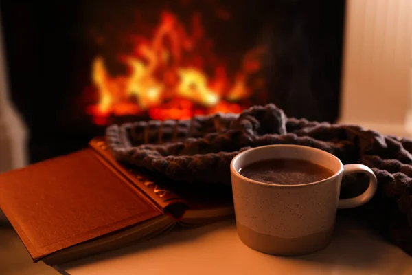 Tasse Heißgetränk Und Buch Auf Dem Tisch Neben Dem Kamin — Stockfoto