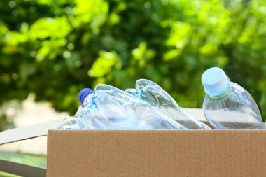 Açık havada kullanılmış plastik şişelerle dolu karton bir kutu. Geri dönüşüm kavramı