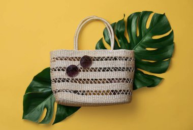 Sarı arka planda saman torbası ve güneş gözlüğü var. Yaz aksesuarları