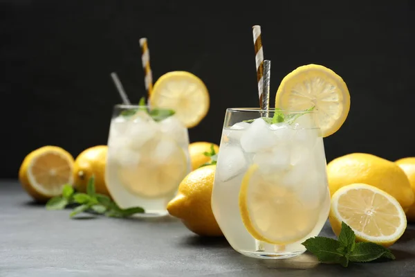 Natural lemonade with mint on grey table against black background, space for text. Summer refreshing drink