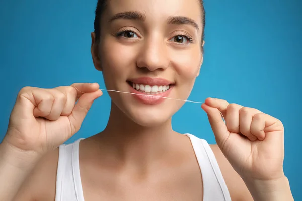 Wanita Muda Flossing Giginya Pada Latar Belakang Biru Dokter Gigi — Stok Foto