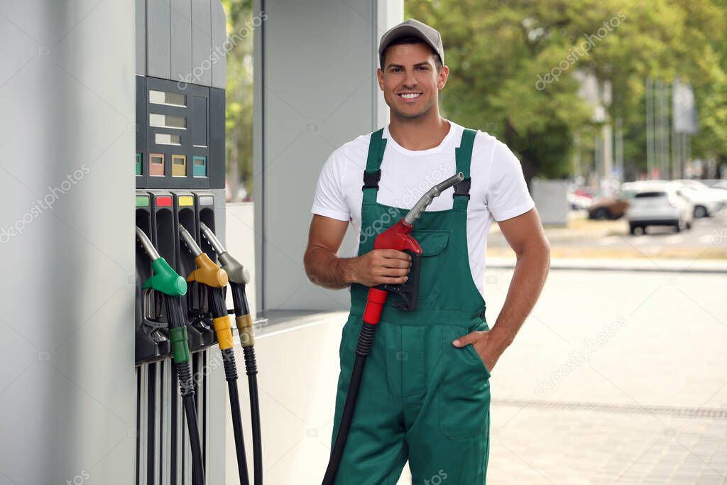 Worker with fuel pump nozzle at modern gas station