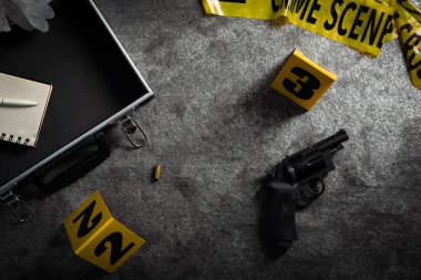 Kanıtlar ve olay yeri işaretleri gri taş arka planda, düz yerde.