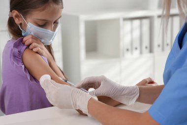 Hastanede küçük bir kızı aşılayan doktor. Sağlık hizmetleri