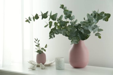 Güzel okaliptüs dalları, mum ve kuş figürleri beyaz masa içinde. İç öge