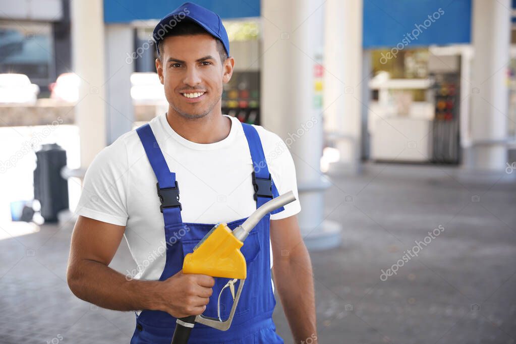 Worker with fuel pump nozzle at gas station