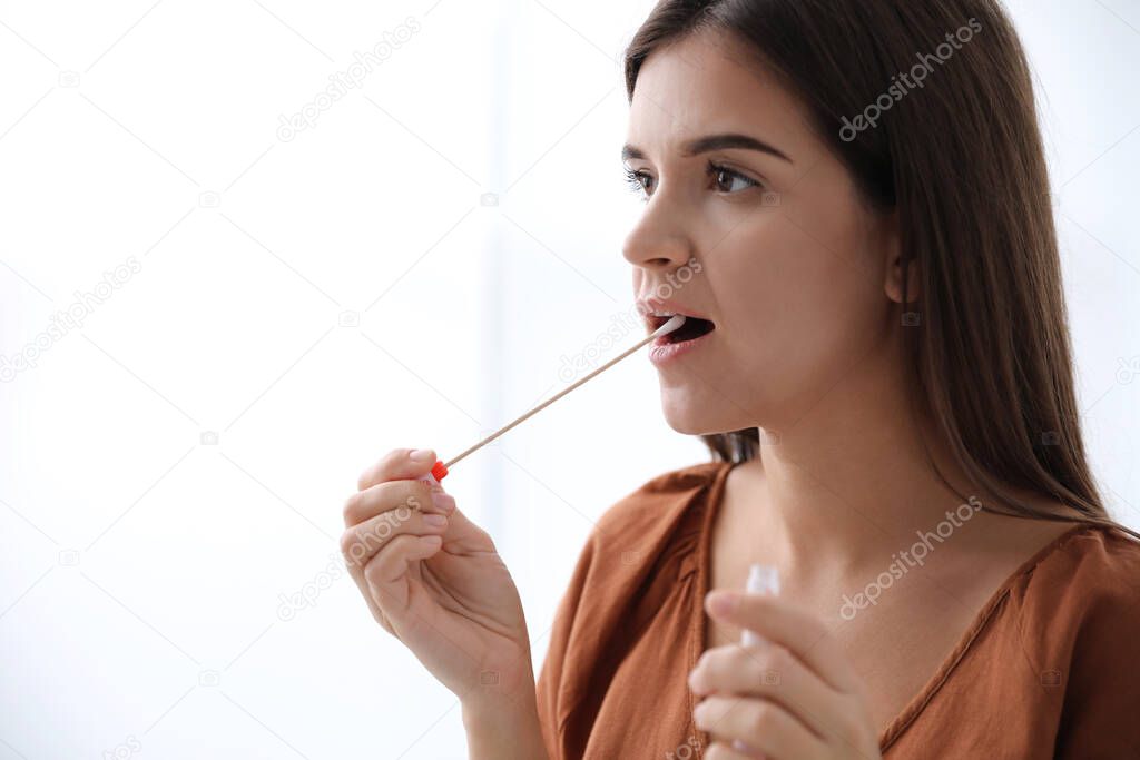 Woman taking sample for DNA test on light background