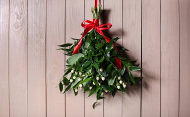 Ahşap duvarda asılı kırmızı kurdeleli ökseotu sürüsü. Geleneksel Noel dekorasyonu