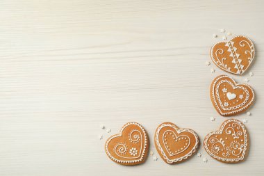 Lezzetli kalp şeklinde zencefilli kurabiyeler beyaz ahşap masada, düz yerde. Metin için boşluk