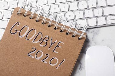 Metinli defter Elveda 2020, bilgisayar klavyesi ve fare beyaz mermer masa, düz yatıyordu