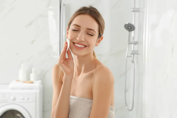 在浴室里用棉垫擦拭脸的年轻女人 — 图库照片