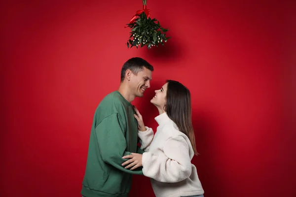 Couple Heureux Debout Sous Bouquet Gui Sur Fond Rouge — Photo