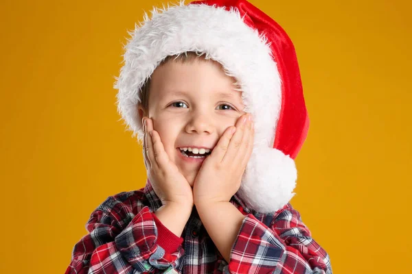 黄色の背景にサンタの帽子のかわいい子供 クリスマスのお祝い — ストック写真