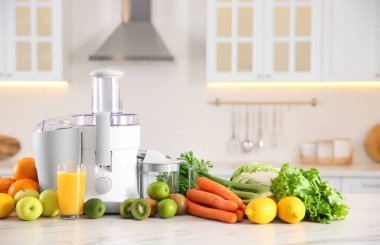 Modern meyve sıkacağı, taze sebze ve meyveler mutfaktaki masada.