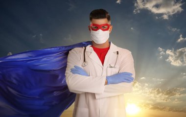 Sağlık çalışanları tehlikeli hastalıklarla savaşıyor. Gökyüzüne karşı poz veren süper kahraman kılığındaki doktor.
