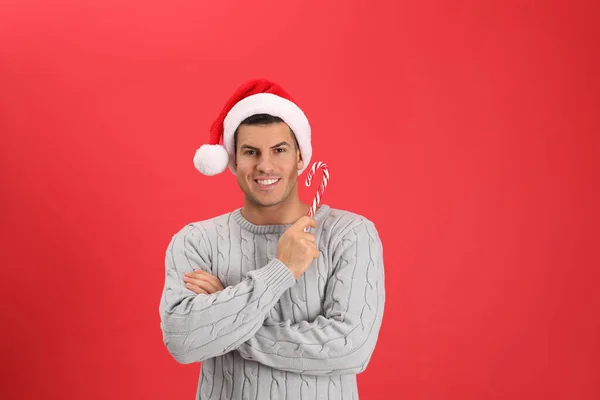 Schöner Mann Mit Weihnachtsmütze Mit Zuckerrohr Auf Rotem Hintergrund — Stockfoto