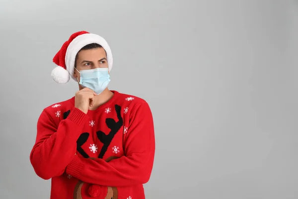 Gri Arka Planda Noel Baba Şapkası Tıbbi Maske Takan Adam — Stok fotoğraf