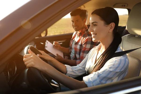 Young woman in car with instructor. Driving school