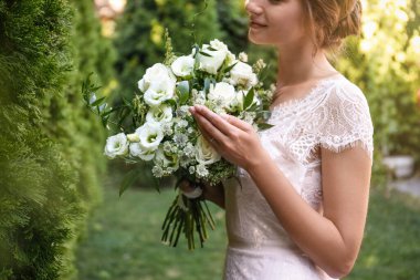 Güzel gelinlik içinde, açık havada buketi olan, yakın plan.