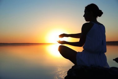 Gün batımında nehrin kenarında bir kadın. İyileştirme kavramı