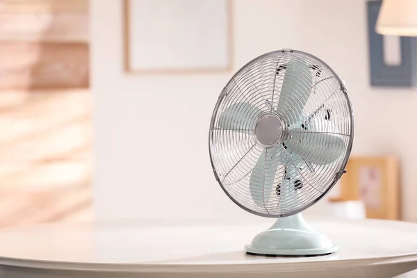 Modern electric fan on white table indoors. Space for text