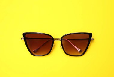 Sarı arkaplanda şık güneş gözlükleri, üst görünüm