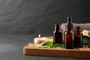 Gri masanın üzerinde aroma yağı şişeleri olan kompozisyon, metin için boşluk