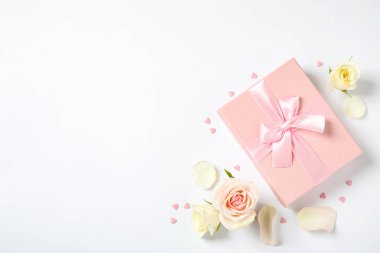 Pembe hediye kutusu ve beyaz arka planda güzel çiçekler. Metin için boşluk