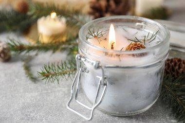 Yakıcı kokulu kozalaklı mum ve gri masada Noel süsü, yakın plan. Metin için boşluk