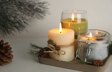 Yanan kokulu kozalaklı mumlar ve ışık masasında Noel dekoru olan kompozisyon