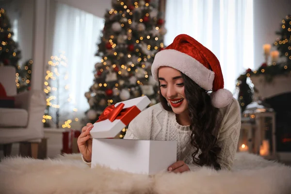 Молодая Женщина Шляпе Санты Открывает Рождественский Подарок Полу Дома — стоковое фото