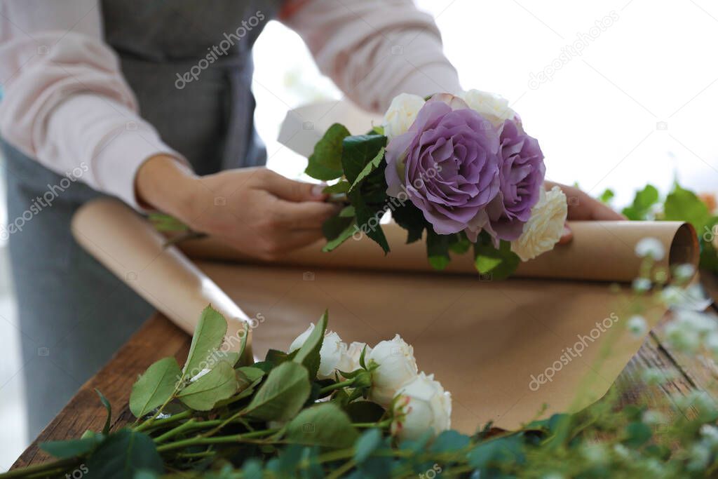 Florist making beautiful wedding bouquet at wooden table, closeup