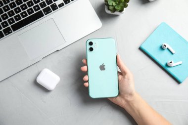 MYKOLAIV, UKRAINE - 10 Temmuz 2020: İphone 11 'i tutan kadın masada, üst manzara