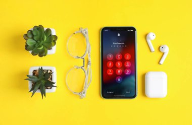 MYKOLAIV, UKRAINE - 10 Temmuz 2020: Sarı zemin üzerinde İphone 11 ve Airpod ile düz kompozisyon, düz yatıyordu