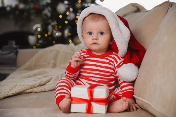 带着圣诞礼物在家里沙发上的圣诞礼帽可爱的小宝宝 — 图库照片