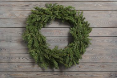 Gri ahşap arka planda köknar dallarından yapılmış Noel çelengi