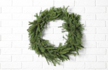 Beyaz tuğla duvardaki köknar dallarından yapılmış Noel çelengi